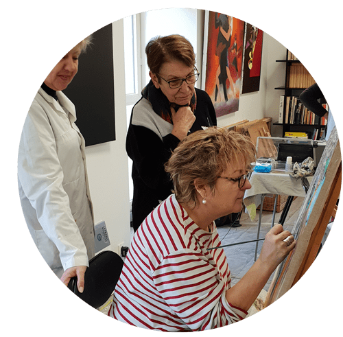 Éliane concentrée sur la retouche du tableau d'une élève de son cours de peinture artistique Eliane Salvat de niort